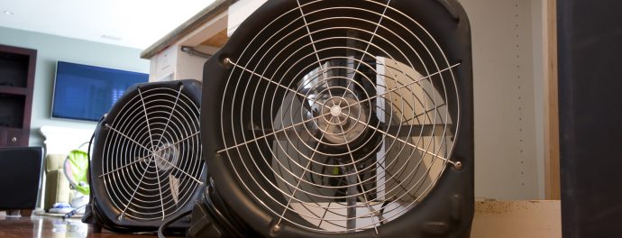 Two industrial fans running to dry out water damaged residential kitchen island from leak